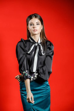 Genç model kırmızı bir arka plan üzerinde rahat kıyafetler içinde stüdyo portre. Siyah gömlek ve mavi etek stüdyoda poz genç kadın 