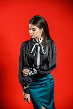 Genç model kırmızı bir arka plan üzerinde rahat kıyafetler içinde stüdyo portre. Siyah gömlek ve mavi etek stüdyoda poz genç kadın 