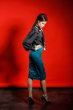 Genç model kırmızı bir arka plan üzerinde rahat kıyafetler içinde stüdyo portre. Siyah gömlek ve mavi etek stüdyoda poz genç kadın 