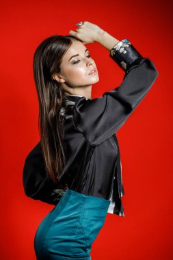 Genç model kırmızı bir arka plan üzerinde rahat kıyafetler içinde stüdyo portre. Siyah gömlek ve mavi etek stüdyoda poz genç kadın 