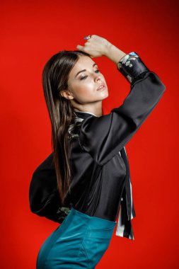 Genç model kırmızı bir arka plan üzerinde rahat kıyafetler içinde stüdyo portre. Siyah gömlek ve mavi etek stüdyoda poz genç kadın 