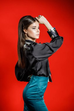 Genç model kırmızı bir arka plan üzerinde rahat kıyafetler içinde stüdyo portre. Siyah gömlek ve mavi etek stüdyoda poz genç kadın 