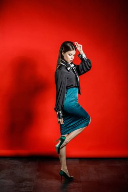 Genç model kırmızı bir arka plan üzerinde rahat kıyafetler içinde stüdyo portre. Siyah gömlek ve mavi etek stüdyoda poz genç kadın 