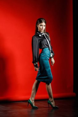 Genç model kırmızı bir arka plan üzerinde rahat kıyafetler içinde stüdyo portre. Siyah gömlek ve mavi etek stüdyoda poz genç kadın 