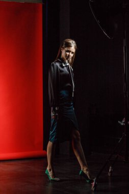 Genç model kırmızı bir arka plan üzerinde rahat kıyafetler içinde stüdyo portre. Siyah gömlek ve mavi etek stüdyoda poz genç kadın 