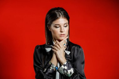 Portre stüdyo portre rahat kıyafetler genç modeli. Üzerinde kırmızı bir arka plan üzerinde boyun duran yay ile siyah gömlek giymiş şık saç kesimi, Genç kadınla 