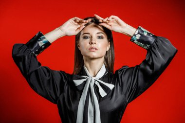 Portre stüdyo portre rahat kıyafetler genç modeli. Üzerinde kırmızı bir arka plan üzerinde boyun duran yay ile siyah gömlek giymiş şık saç kesimi, Genç kadınla 