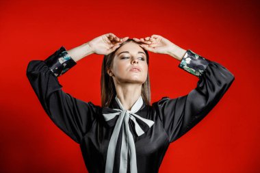 Portre stüdyo portre rahat kıyafetler genç modeli. Üzerinde kırmızı bir arka plan üzerinde boyun duran yay ile siyah gömlek giymiş şık saç kesimi, Genç kadınla 