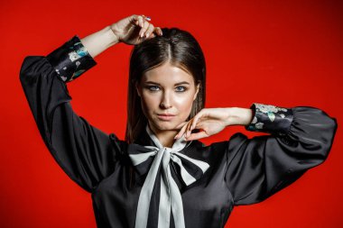 Portre stüdyo portre rahat kıyafetler genç modeli. Üzerinde kırmızı bir arka plan üzerinde boyun duran yay ile siyah gömlek giymiş şık saç kesimi, Genç kadınla 