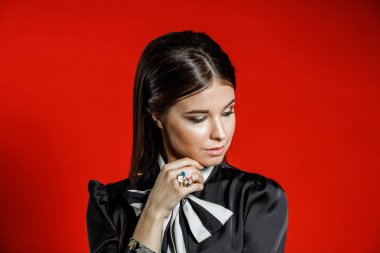 Portre stüdyo portre rahat kıyafetler genç modeli. Üzerinde kırmızı bir arka plan üzerinde boyun duran yay ile siyah gömlek giymiş şık saç kesimi, Genç kadınla 