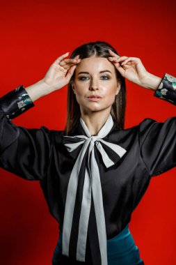 Portre stüdyo portre rahat kıyafetler genç modeli. Üzerinde kırmızı bir arka plan üzerinde boyun duran yay ile siyah gömlek giymiş şık saç kesimi, Genç kadınla 