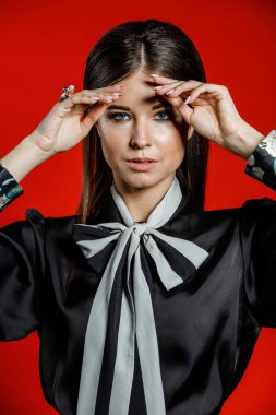 Portre stüdyo portre rahat kıyafetler genç modeli. Üzerinde kırmızı bir arka plan üzerinde boyun duran yay ile siyah gömlek giymiş şık saç kesimi, Genç kadınla 