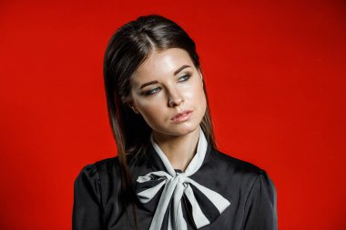 Portre stüdyo portre rahat kıyafetler genç modeli. Üzerinde kırmızı bir arka plan üzerinde boyun duran yay ile siyah gömlek giymiş şık saç kesimi, Genç kadınla 