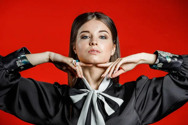 Portre stüdyo portre rahat kıyafetler genç modeli. Üzerinde kırmızı bir arka plan üzerinde boyun duran yay ile siyah gömlek giymiş şık saç kesimi, Genç kadınla 