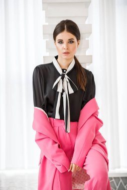 Pembe takım elbise ve lüks ev iç merdiven üzerinde duran siyah t-shirt giyen güzel esmer kadın portresi stüdyo 