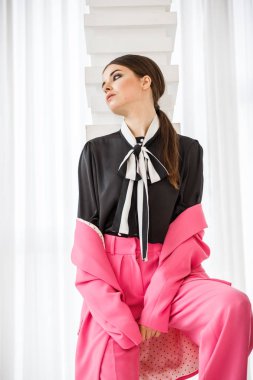 Pembe takım elbise ve lüks ev iç merdiven üzerinde duran siyah t-shirt giyen güzel esmer kadın portresi stüdyo 