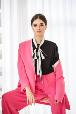 Pembe takım elbise ve lüks ev iç merdiven üzerinde duran siyah t-shirt giyen güzel esmer kadın portresi stüdyo 