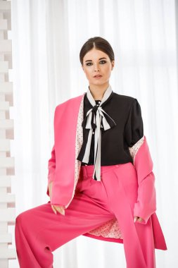 Pembe takım elbise ve lüks ev iç merdiven üzerinde duran siyah t-shirt giyen güzel esmer kadın portresi stüdyo 