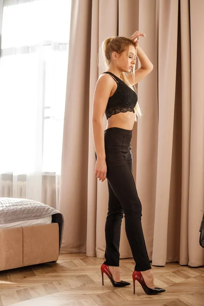 明るい室内で立っている黒のカジュアルな服で美しいブロンドの女の子 — ストック写真