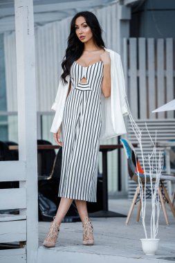 Çizgili siyah beyaz elbiseli güzel genç esmer kadın açık portresi. Kafe iç duran kıvırcık kadın