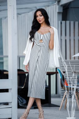 Çizgili siyah beyaz elbiseli güzel genç esmer kadın açık portresi. Kafe iç duran kıvırcık kadın