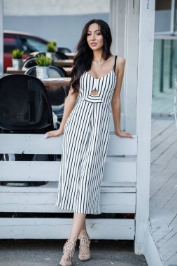 Çizgili siyah beyaz elbiseli güzel genç esmer kadın açık portresi. Kafe iç duran kıvırcık kadın