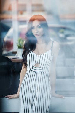 Çizgili siyah beyaz elbiseli güzel genç esmer kadın açık portresi. Kafe iç duran kıvırcık kadın