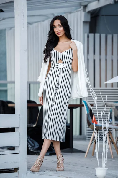 Çizgili siyah beyaz elbiseli güzel genç esmer kadın açık portresi. Kafe iç duran kıvırcık kadın