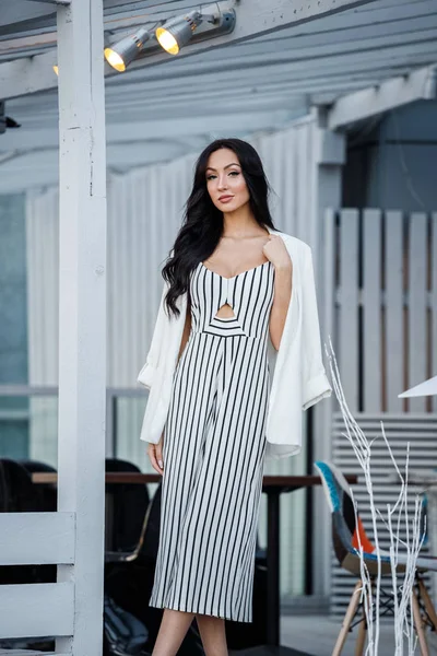 Çizgili siyah beyaz elbiseli güzel genç esmer kadın açık portresi. Kafe iç duran kıvırcık kadın