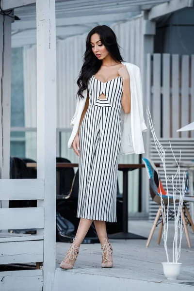 Çizgili siyah beyaz elbiseli güzel genç esmer kadın açık portresi. Kafe iç duran kıvırcık kadın