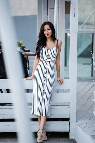 Çizgili siyah beyaz elbiseli güzel genç esmer kadın açık portresi. Kafe iç duran kıvırcık kadın