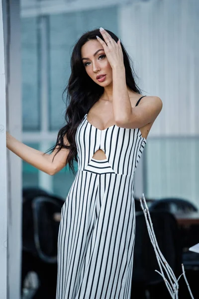 Çizgili siyah beyaz elbiseli güzel genç esmer kadın açık portresi. Kafe iç duran kıvırcık kadın