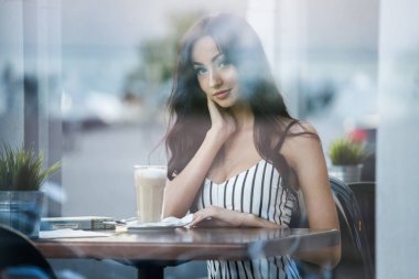 Çizgili siyah beyaz elbiseli güzel genç esmer kadın portresi. Kahve içme ve kafe iç kitap okuma kıvırcık kadın