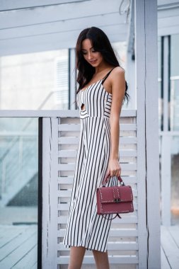 Çizgili siyah beyaz elbiseli güzel genç esmer kadın açık portresi. Kafe iç duran kıvırcık kadın