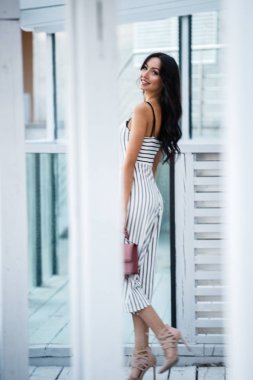 Çizgili siyah beyaz elbiseli güzel genç esmer kadın açık portresi. Kafe iç duran kıvırcık kadın