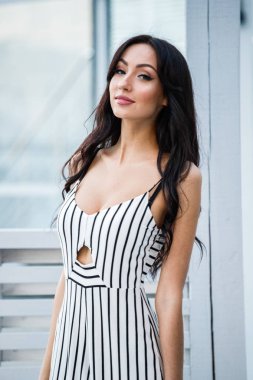 Çizgili siyah beyaz elbiseli güzel genç esmer kadın açık portresi. Kafe iç duran kıvırcık kadın