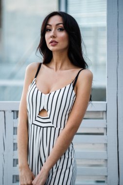 Çizgili siyah beyaz elbiseli güzel genç esmer kadın açık portresi. Kafe iç duran kıvırcık kadın