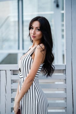 Çizgili siyah beyaz elbiseli güzel genç esmer kadın açık portresi. Kafe iç duran kıvırcık kadın