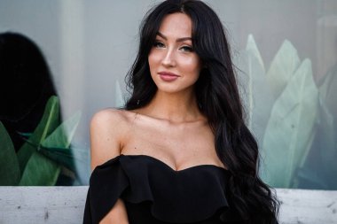 Portre portre ile şık makyaj, yeşil bitkiler arka plan siyah elbiseli güzel genç esmer kadının