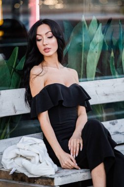 Portre portre ile şık makyaj, yeşil bitkiler arka plan siyah elbiseli güzel genç esmer kadının