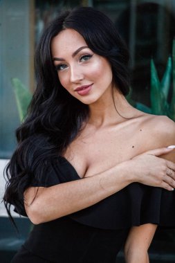 Portre portre ile şık makyaj, yeşil bitkiler arka plan siyah elbiseli güzel genç esmer kadının