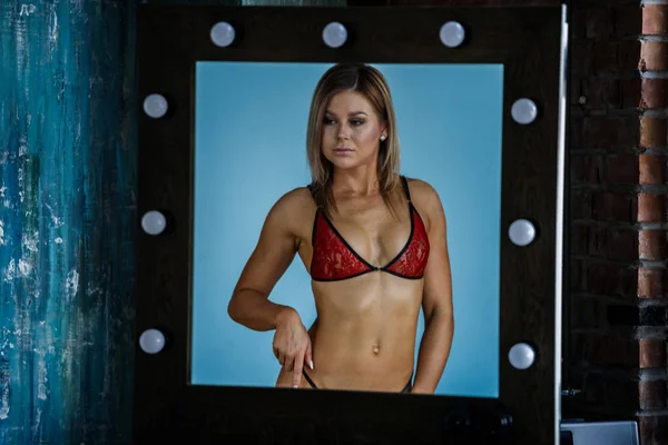 Kalan kırmızı-siyah cinsel iç çamaşırı giyen güzellik sarışın kadın portresi Studio kapatmak için mavi duvar arka planı yansıtmadaki 