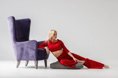 Moda studio mor koltuk ile beyaz oda iç modelinde güzellik portresi. Kırmızı casual elbise giymiş genç kadının güzellik atış 