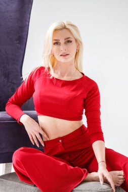 Moda studio mor koltuk ile beyaz oda iç modelinde güzellik portresi. Kırmızı casual elbise giymiş genç kadının güzellik atış 