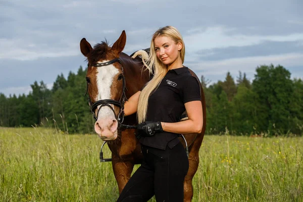 昼間で馬に乗って美容金髪女性の屋外撮影 競馬場で乗馬を楽しむスポーティな服の若い女性 — ストック写真