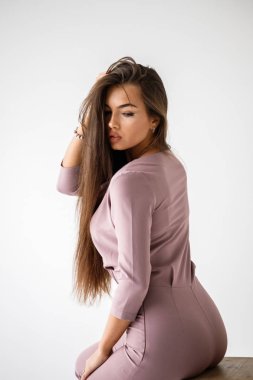 Casual mor kıyafet giyen, ahşap sandalye, beyaz stüdyo arka plan üzerinde oturan güzel esmer kadın portresi