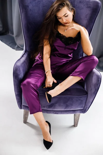 Stüdyo mor pijama genç esmer kadın portresi. Güzellik kadını ev iç, mor koltuk oturma