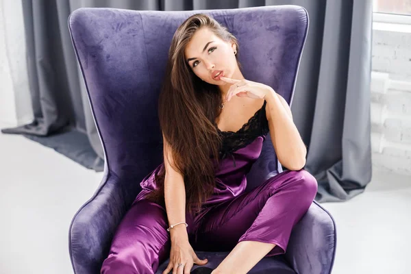 Stüdyo mor pijama genç esmer kadın portresi. Güzellik kadını ev iç, mor koltuk oturma