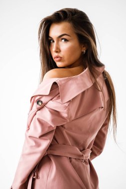 Pembe ceket ayakta beyaz stüdyo arka plan üzerinde giyen güzel esmer kadın portresi
