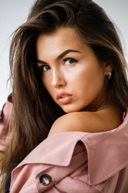 Pembe ceket ayakta beyaz stüdyo arka plan üzerinde giyen güzel esmer kadın portresi portre